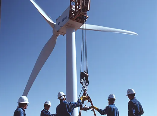 A group of engineers and a Procurement Specialist in Florida overseeing the installation and supply chain of a large wind turbine.