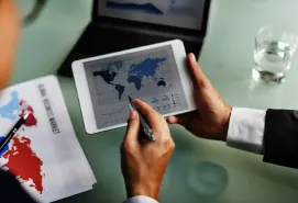 A Procurement Specialist in California using a tablet to analyze global market trends and supply chain data on a digital world map.