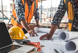 Project managers reviewing blueprints at a job site, illustrating the hands-on approach of Best Procurement Consulting Firms in New Jersey for industrial operations.