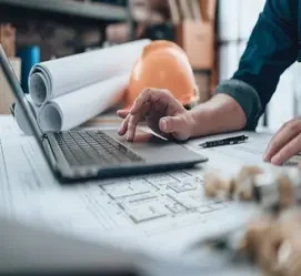 Construction professional reviewing architectural plans on a laptop