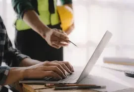 Construction professionals reviewing project plans on a laptop